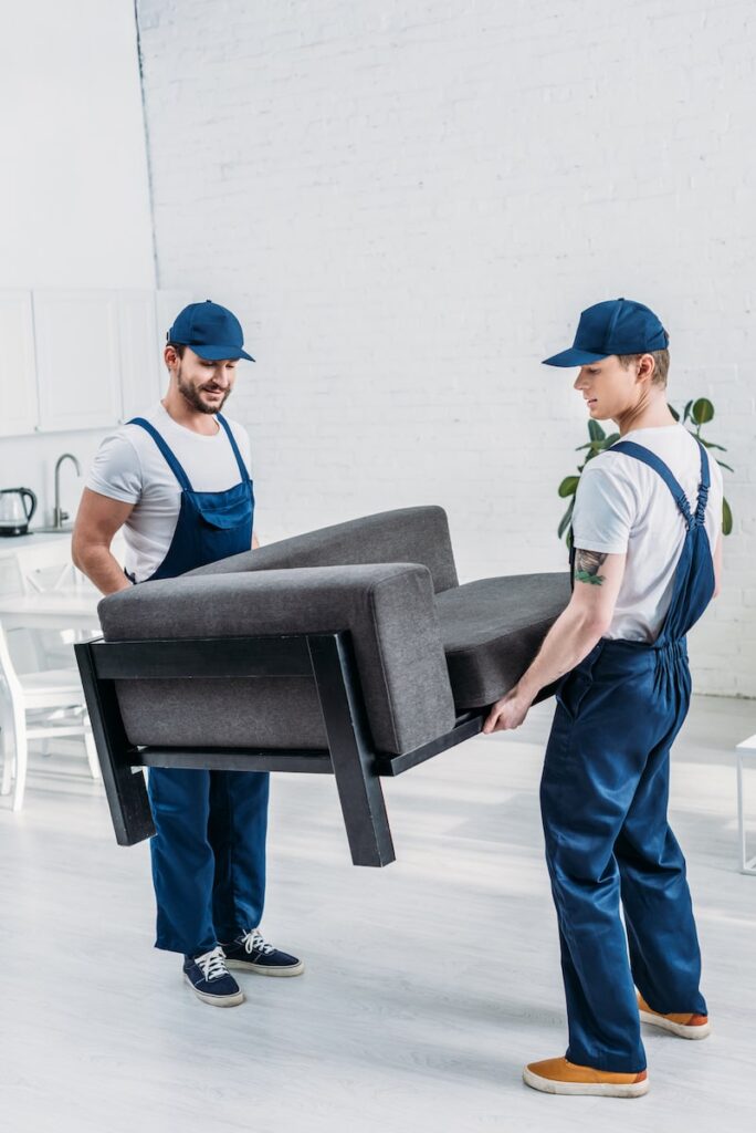 two movers in uniform transporting furniture in ap 2023 04 28 04 25 00 utc min